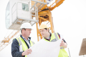 Construction worker engineer reviewing blueprints at highrise construction site