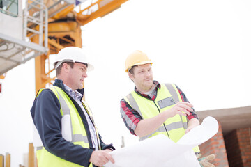 Construction worker engineer reviewing blueprints at highrise construction site