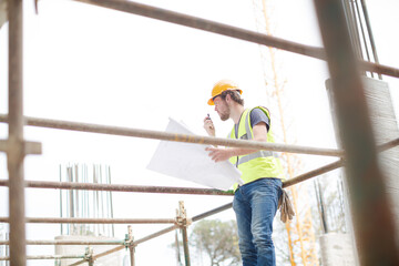 Engineer reviewing blueprints at high rise construction site