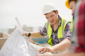 Construction worker engineer reviewing blueprints at highrise construction site