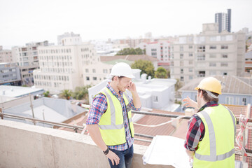 Construction worker engineer reviewing blueprints at highrise construction site