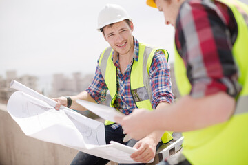 Fototapeta premium Construction worker engineer reviewing blueprints at highrise construction site