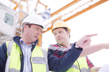 Construction worker engineer reviewing blueprints at highrise construction site