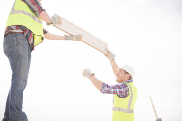 Construction workers lifting part at highrise construction site