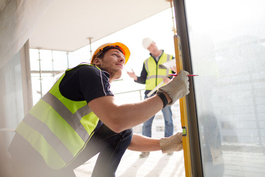 Construction Worker Measuring Window At Construction Site