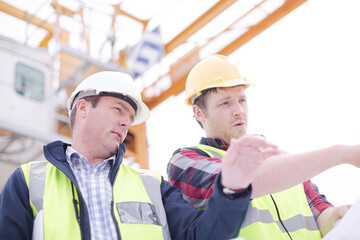 Construction worker engineer reviewing blueprints at highrise construction site
