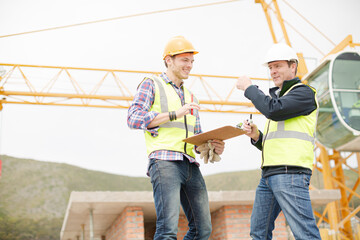 Construction workers with clipboard talking at construction site