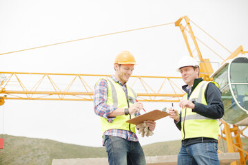 Construction workers with clipboard talking at construction site