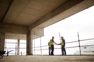 Construction workers handshaking at highrise construction site