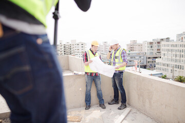 Construction worker engineer reviewing blueprints at highrise construction site