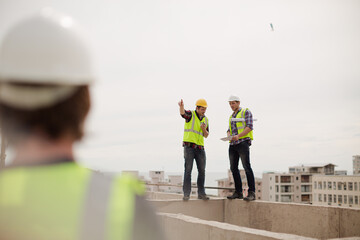 Construction worker and engineer talking at highrise construction site