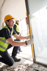 Construction worker measuring window at construction site