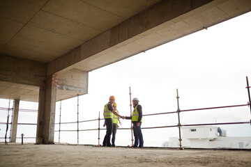 Construction workers handshaking at highrise construction site
