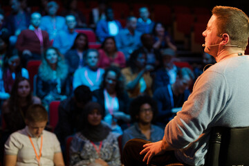 Audience watching male speaker in wheelchair talking on stage
