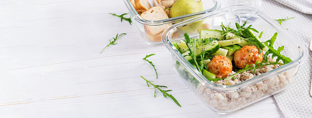 Lunch box filled with oatmeal, cucumber salad, and nuts, bread, pear on white wooden background. Lunchbox dinner. Banner