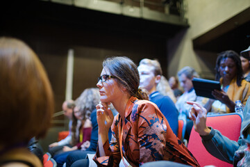 Attentive businesswoman taking in notes in conference audience
