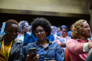 Obraz premium Man and woman with with smart phone in conference audience