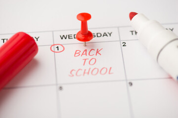 Closeup photo of mark on calendar at first red inscription back to school with red pushpin and...