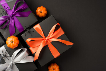 Top view photo of halloween composition three black gift boxes with violet orange and white ribbon...