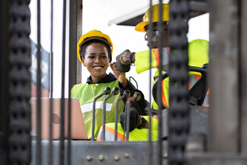 Two African American male and female worker in uniform and helmet driving and operating on diesel...
