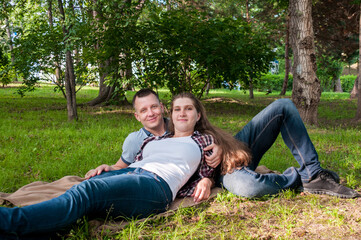 A young couple, a guy and a girl, relax in the park in the summer