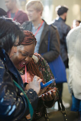 Smiling businesswomen using smart phone in conference audience
