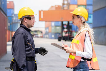 Portrait of foreman or supervisor in uniform and wearing yellow safety helmet checking products on document paper before control loading container box from cargo freight ship for import export. cargo