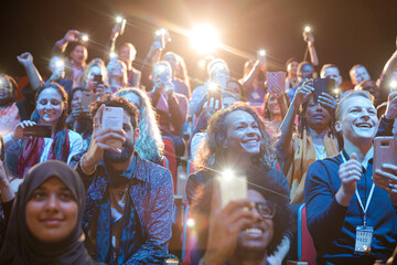 Fototapeta na wymiar Eager audience with smart phone flashlights in dark auditorium