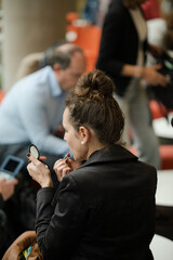 Woman applying make up in hall of auditorium