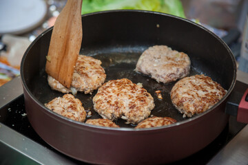 Burger patties are fried in a frying pan.