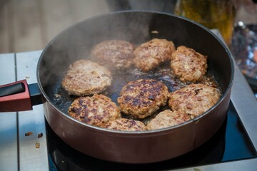 Burger patties are fried in a frying pan.