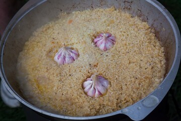 Fresh pilaf with garlic is cooked in a cauldron.