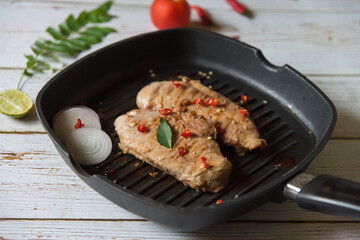 Grilled chicken steak and condiments in a cooking pan. Close up.