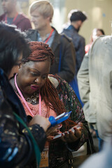 Smiling businesswomen using smart phone in conference audience