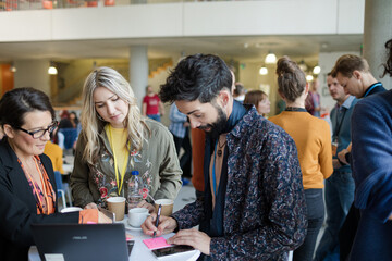 Business people using laptop during conference break