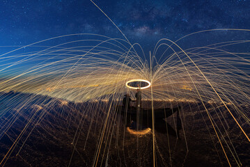 Showers of hot glowing sparks from spinning steel wool on the rock and beach