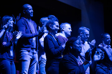 Audience clapping in dark room