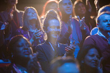 Excited audience clapping in dark room