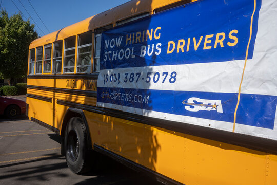 Lake Oswego, OR, USA - Sep 8, 2021: Now Hiring School Bus Drivers Banner Is Seen Hanging On One Side Of An Empty School Bus Operated By STA (Student Transportation Of America) In Lake Oswego, Oregon.