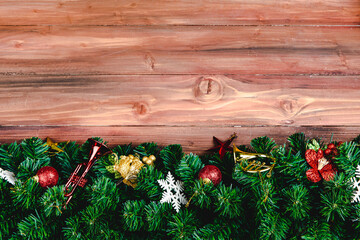 Christmas decoration background with copy space in middle horizontal lay out, fake pine branches and Xmas ornaments decorative props at top and bottom border, top view © Bangkok Click Studio