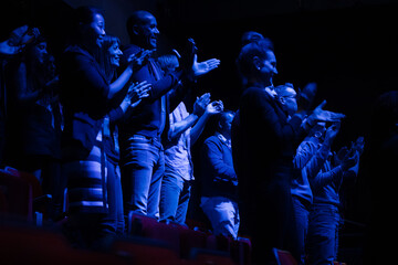 Audience clapping in dark room