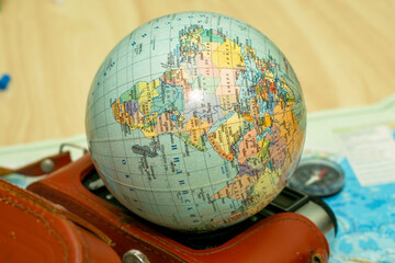 an old camera on a geographical map of the world instead of a globe lens the concept of travel tourism
