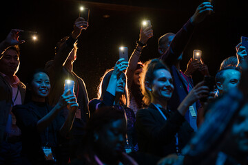 Fototapeta premium Excited audience with smart phone flashlights cheering