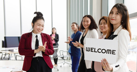 Group of Asian female  businesspeople joins together greeting and hold welcome words for a sign of happiness and pleasure for coming of something or someone