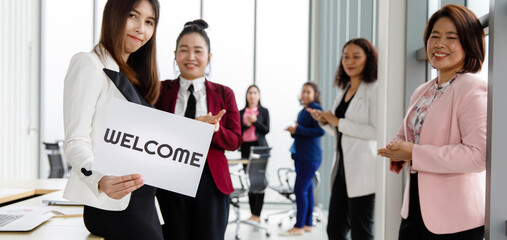 Group of Asian female  businesspeople joins together greeting and hold welcome words for a sign of happiness and pleasure for coming of something or someone