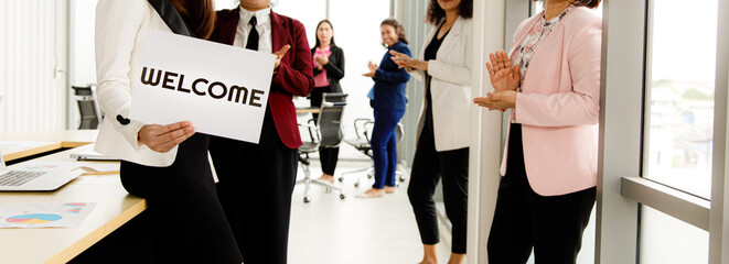 Group of businesspeople joins together greeting and hold welcome words for a sign of happiness and...