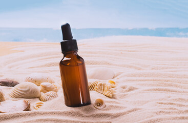 Glass bottle with essential oil serum cosmetic product background of seashells beach sand, product...