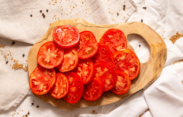 Wooden cutting board with tomato slices on top.
