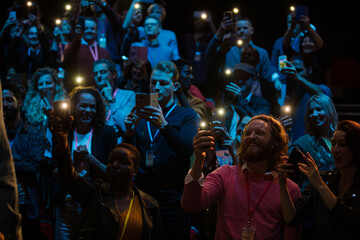 Smiling audience using smart phone flashlights for speaker