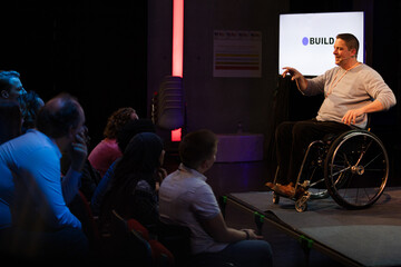 Smiling male speaker in wheelchair on stage